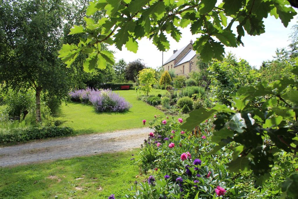 a garden with flowers and a house in the background at Au Jardin Des Violettes in Mahéru