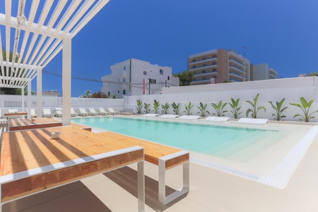 uma piscina com uma mesa de madeira e bancos num edifício em White Apartments - Adults Only em Cidade de Ibiza