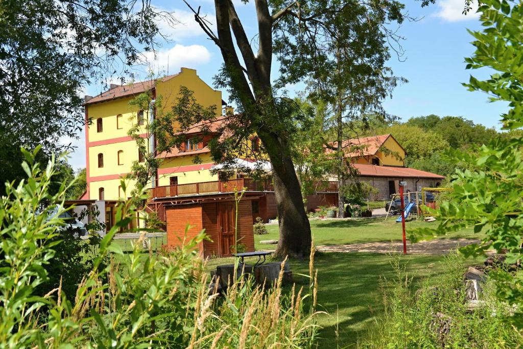 a building with a tree in a park at Penzion Mlýn Sedlec in Sedlec