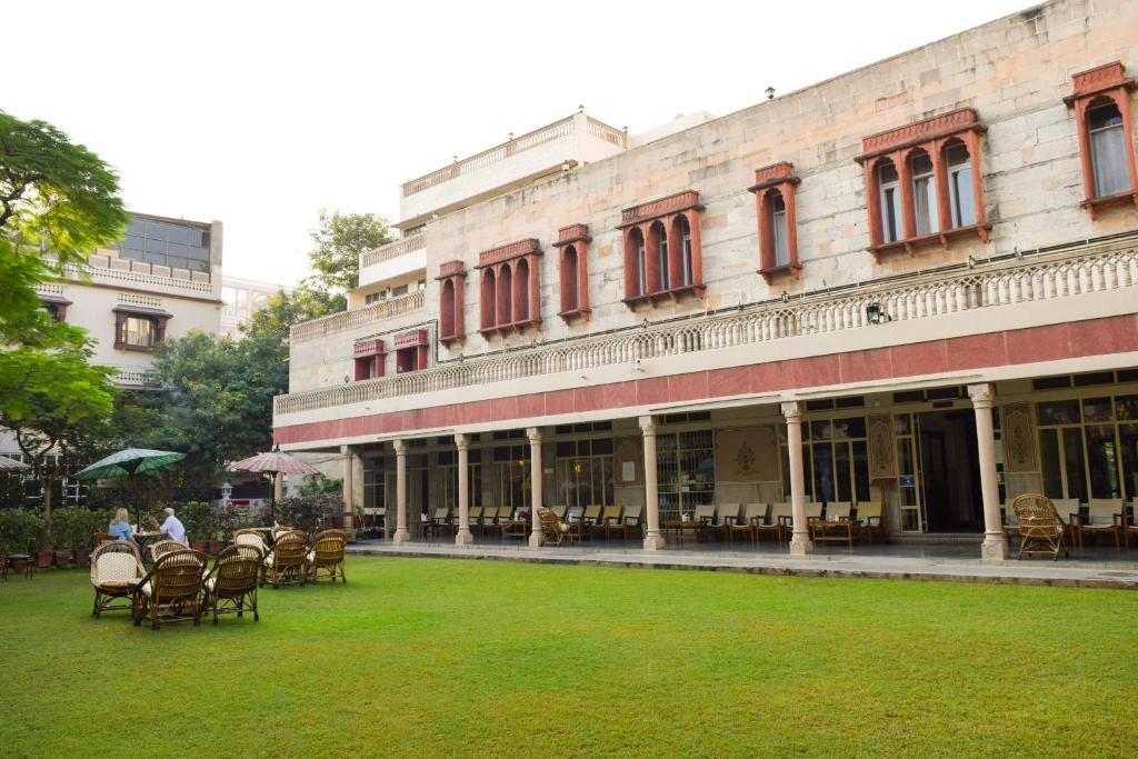 a building with chairs and tables in a yard at Hotel Arya Niwas in Jaipur