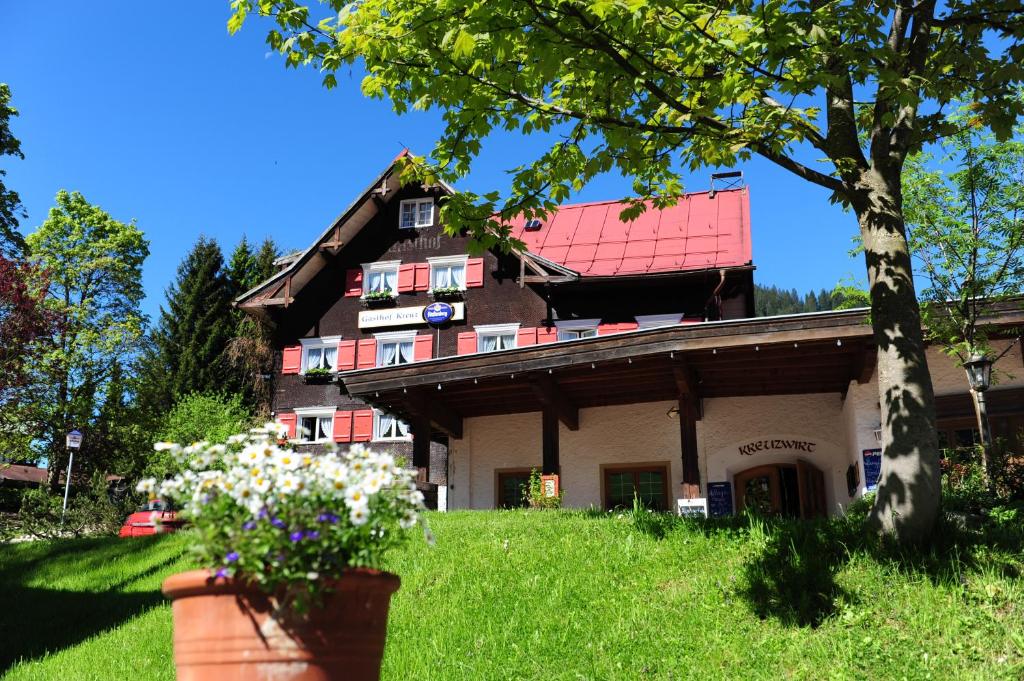 a house with a red roof on a green lawn at Landhaus Beate in Hirschegg