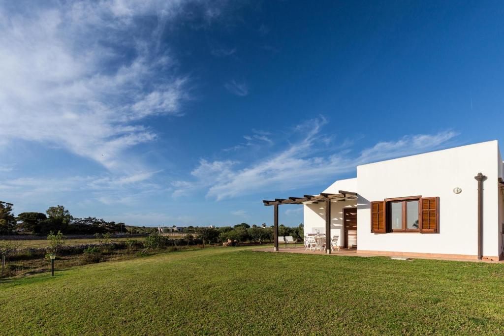 a white house with a green field in the foreground at Le Casette a Favignana in Favignana