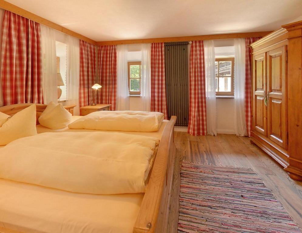 two beds in a bedroom with red curtains at Gasthof Ochsenwirt in Oberaudorf