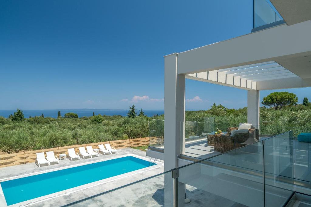 una casa de cristal con piscina y sillas en Bianca Luxury Villa - Private Heated Pool, en Akrotiri