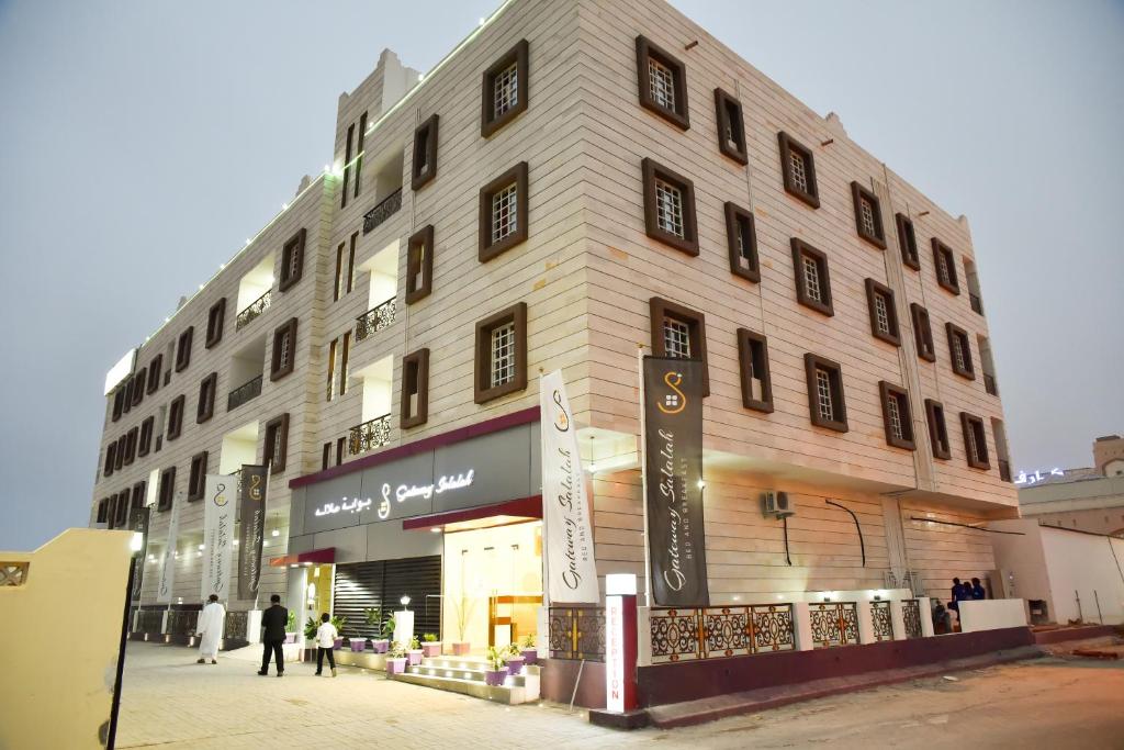 Gateway Salalah Apartments في صلالة: مبنى كبير فيه ناس تمشي امامه