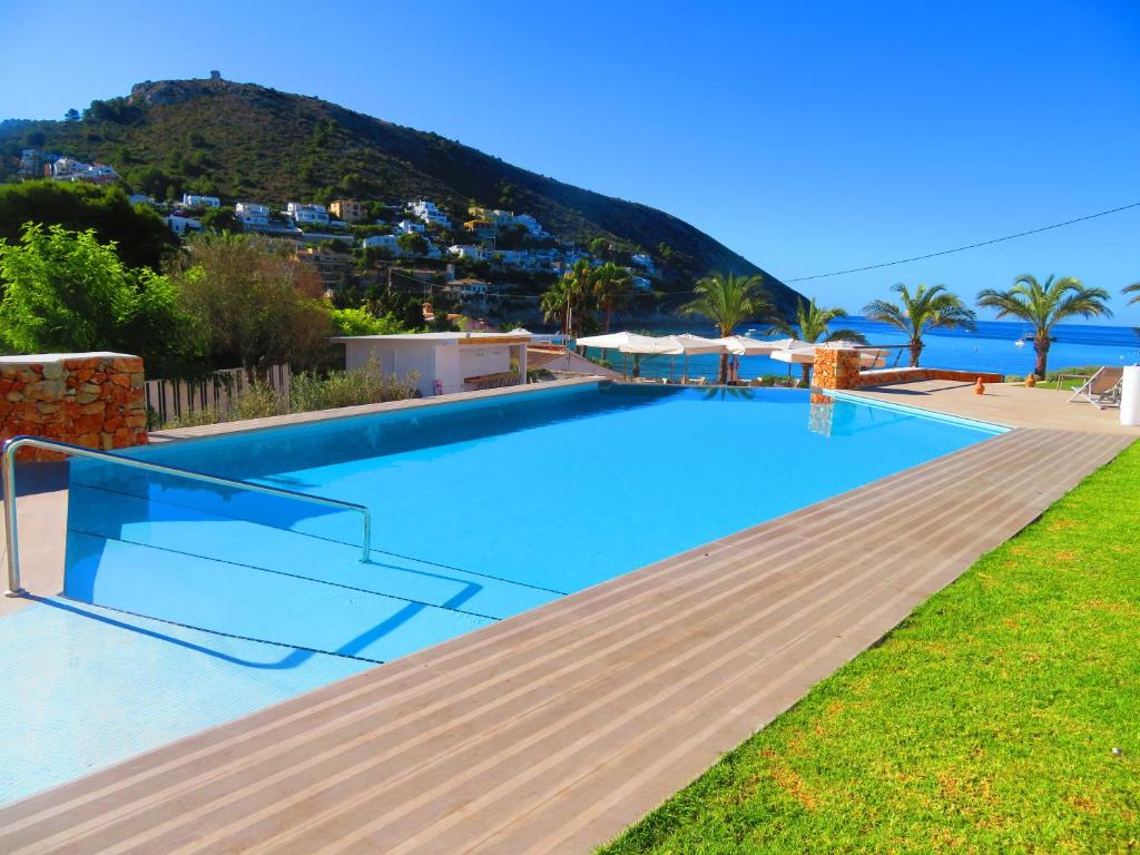 a large swimming pool with a view of the ocean at HOTEL MAÑET in Moraira