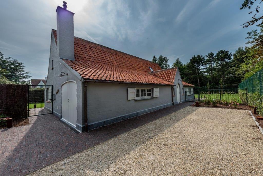 un petit bâtiment blanc avec un toit rouge dans l'établissement Amber, à Nieuport