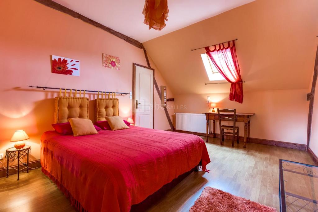 Un dormitorio con una gran cama roja y una mesa en La Ferme de l'isle et sa Roulotte en Avaray