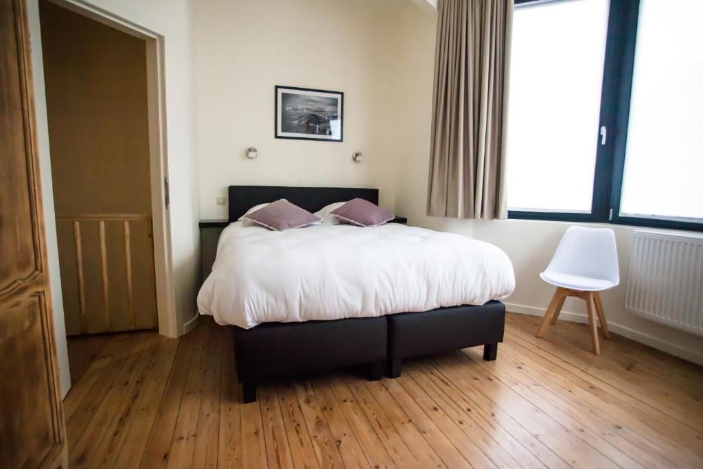 een slaapkamer met een bed met witte lakens en paarse kussens bij Maison d'O in Oostende