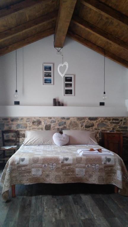 a bedroom with a large bed with a stone wall at Agriturismo Giumin in Rocchetta di Vara