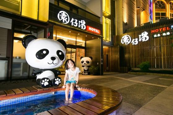 Une petite fille assise dans une piscine avec un ours géant dans l'établissement Garden Spring Hotel, à Jiaoxi
