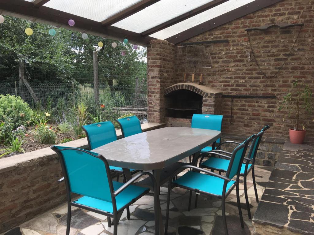 a table and chairs on a patio with a brick oven at Gite Au Cortil in Chevetogne