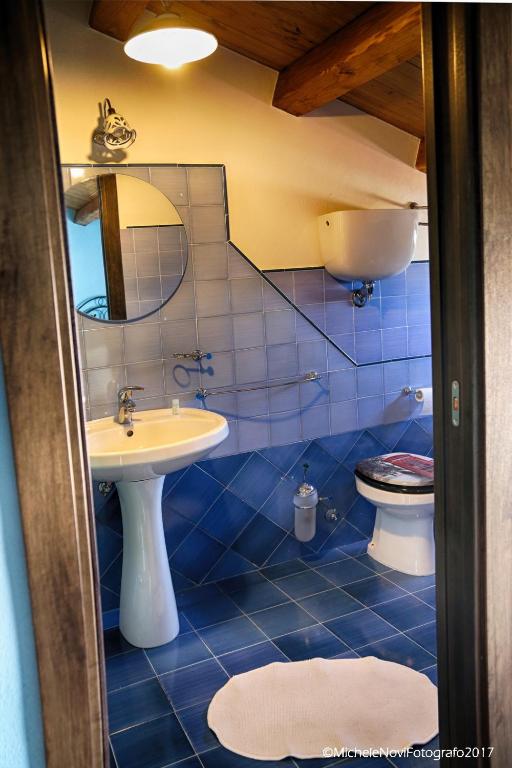 a blue tiled bathroom with a sink and a toilet at La Casa di Ivana in San Nicola Arcella