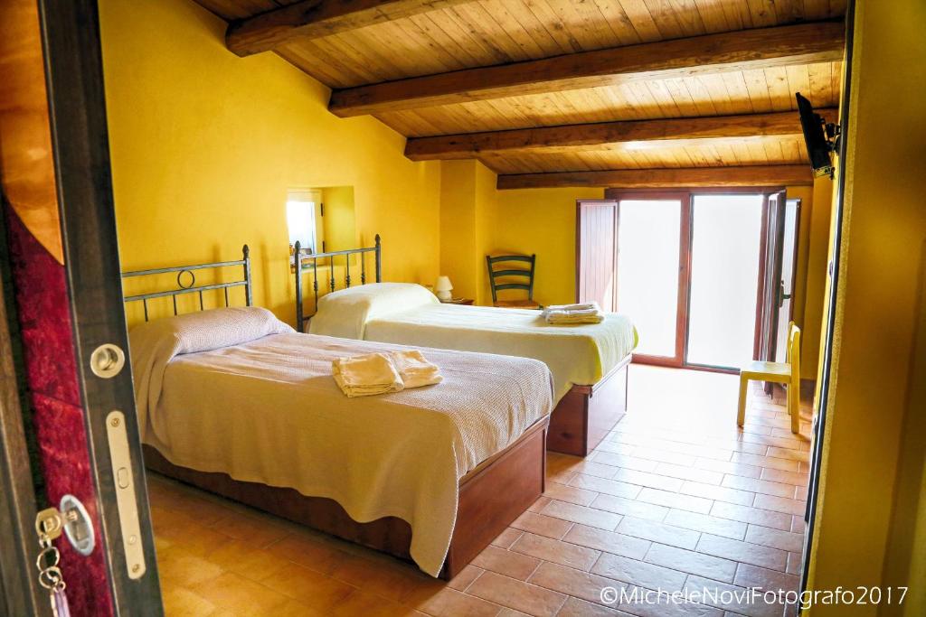La Casa di Ivana في سان نيكولا أرسيلا: سريرين في غرفة بجدران صفراء