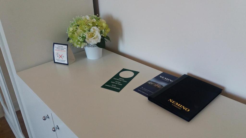White dresser top with potted flowers, brochures and a green door-hanger card, tidy presentation.
