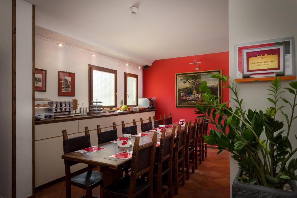 a dining room with a table and chairs and red walls at Hotel Kursaal & Ausonia in Florence