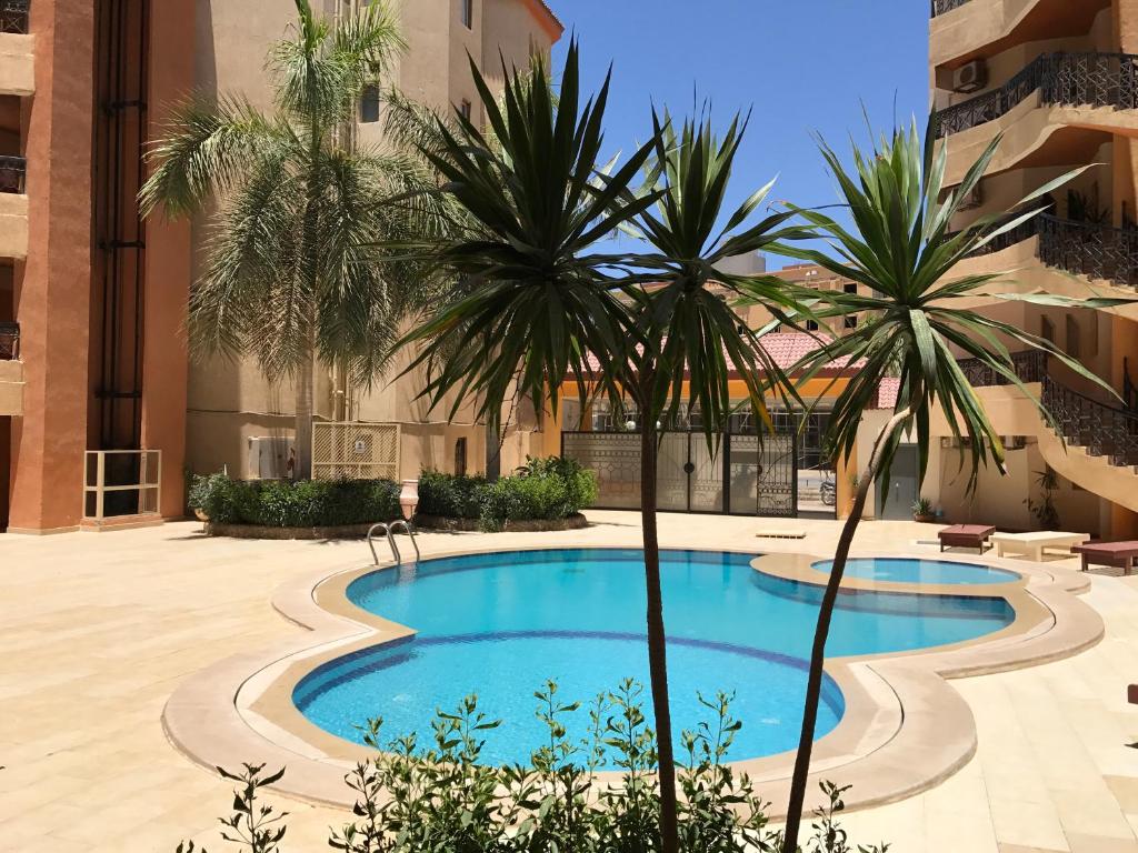 a swimming pool in the middle of a building with palm trees at Regency Towers Apartments in Hurghada