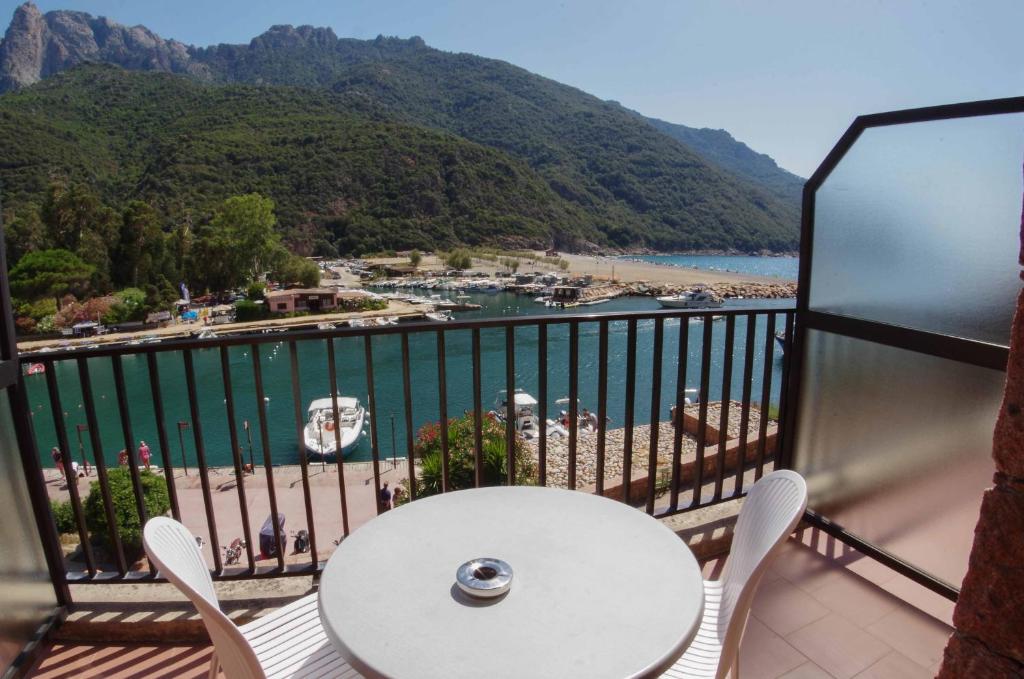 a balcony with a table and chairs and a view of a harbor at Hôtel Le Romantique in Porto Ota