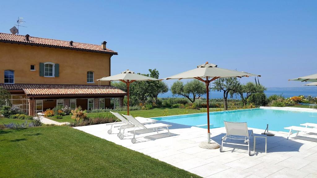 una piscina con sedie e ombrelloni accanto a una casa di Ca Muretta Relais a Bardolino