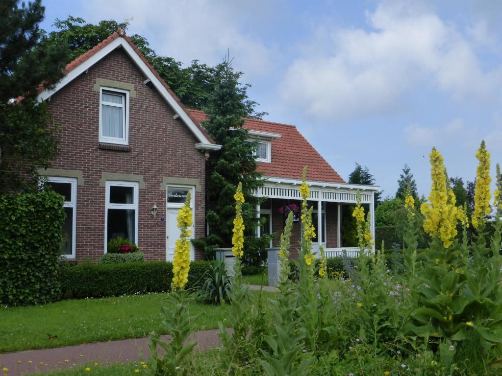 a brick house with yellow flowers in the yard at B&B Berkenrode in Rockanje