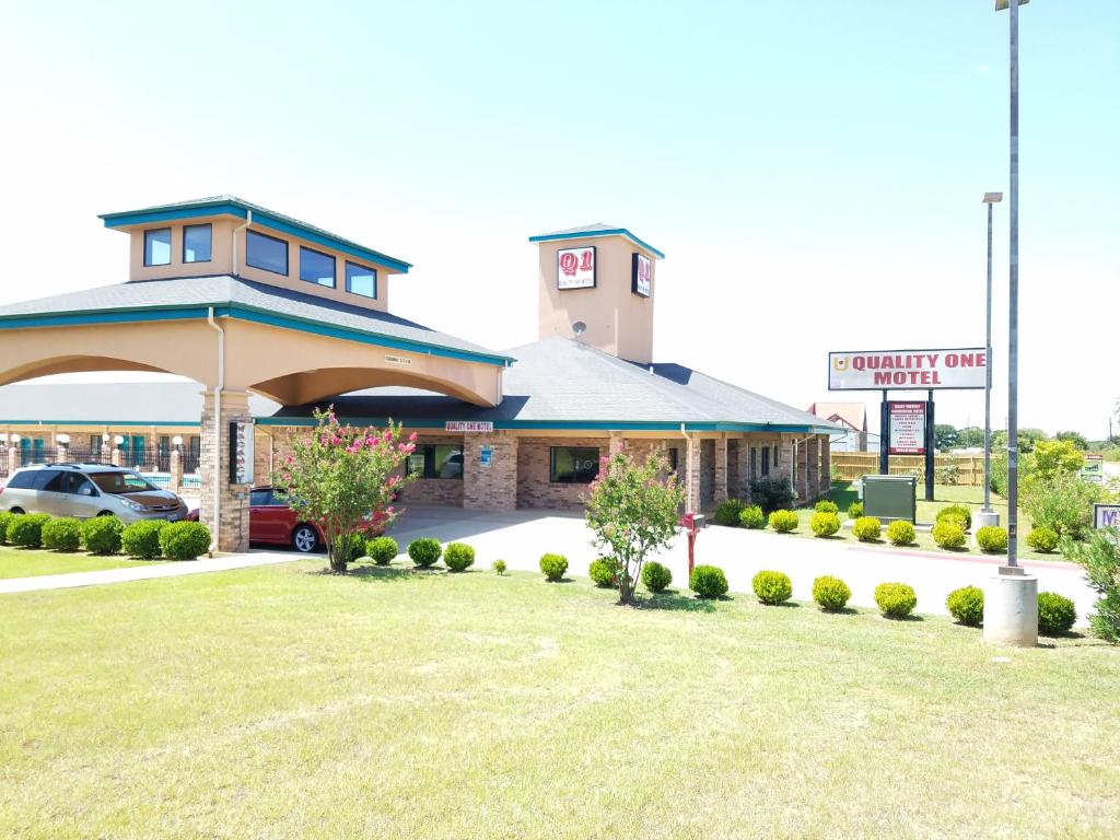 a building with a car parked in a parking lot at Quality One Motel in Weatherford