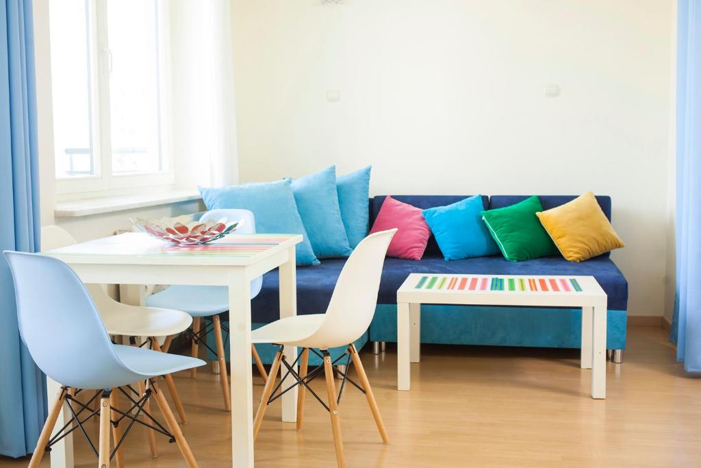 a living room with a blue couch with colorful pillows at Royal Park Executive Apt in Warsaw