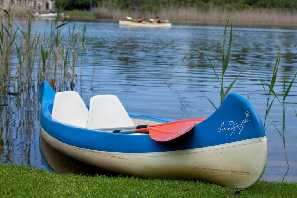 um pequeno barco sentado na costa de uma massa de água em Serendipity Country House & Restaurant em Wilderness