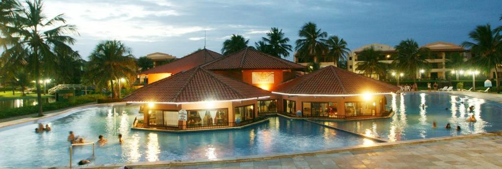 una gran piscina en un complejo por la noche en Apartamento Aquaville Resort, en Aquiraz