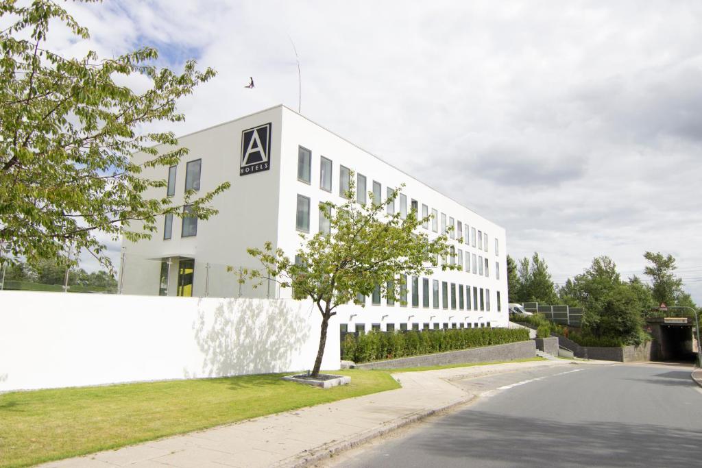 un bâtiment blanc avec un arbre devant lui dans l'établissement A Hotels Glostrup, à Glostrup