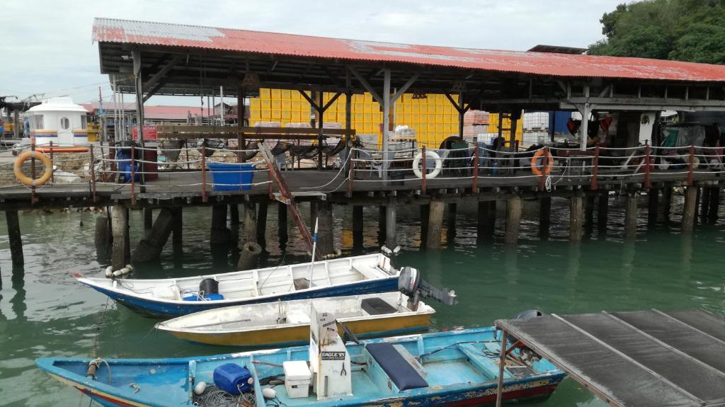 zwei Boote im Wasser neben einem Pier in der Unterkunft Pangkor Home Sea Village in Pulau Pangkor