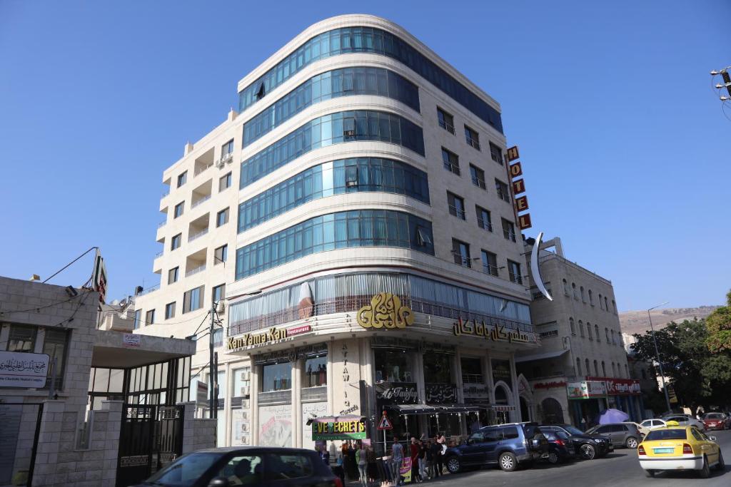 un edificio blanco alto en una calle de la ciudad con coches en Royal Suites en Nablus