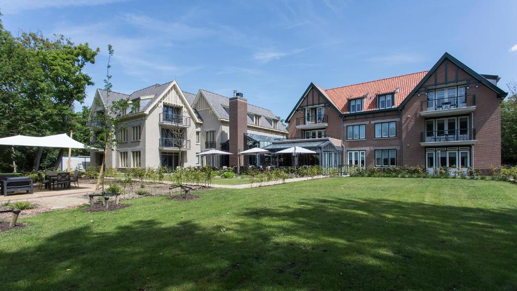 un grand bâtiment avec une pelouse devant lui dans l'établissement Mezger Lodges, à Domburg