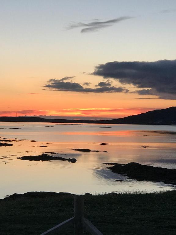 einen Sonnenuntergang über einem großen Wasserkörper in der Unterkunft An Taigh Mòr in Eriskay