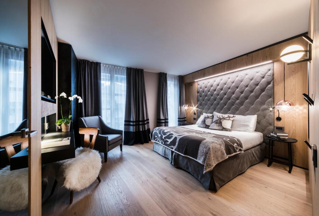 una camera d'albergo con un grande letto e una sedia di Majestic Hotel a Madonna di Campiglio