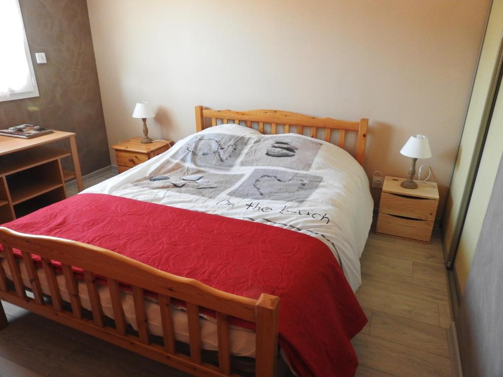 a bedroom with a wooden bed with a red blanket at Les logis de Lucie in Selonnet