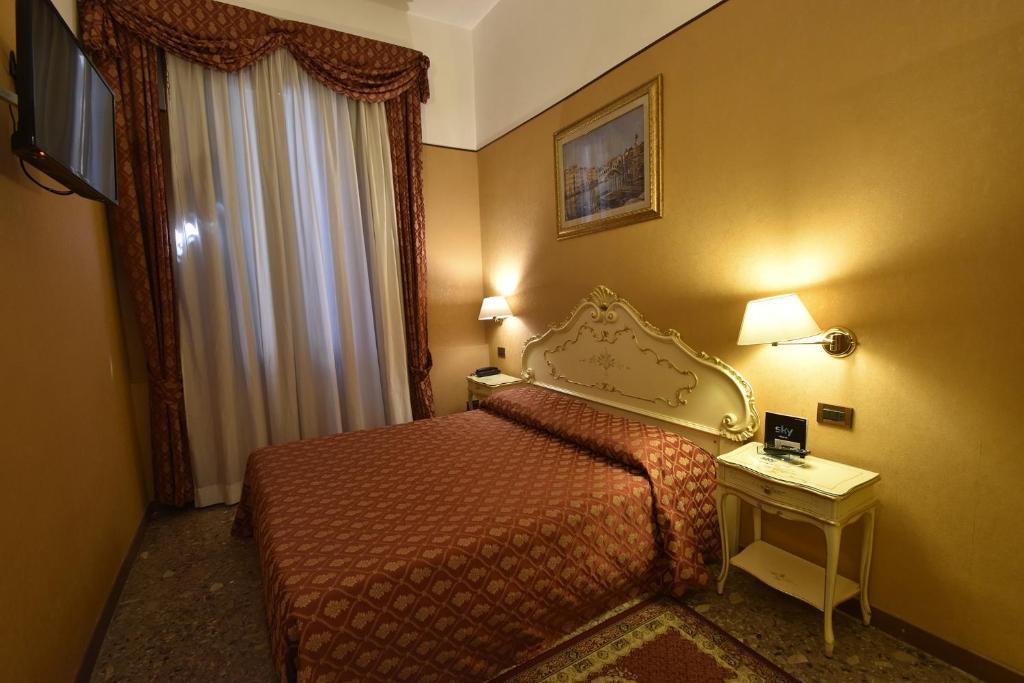 a hotel room with a bed and a table and a window at Locanda Poste Vecie in Venice