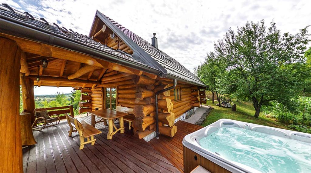 a wooden cabin with a hot tub on a deck at BeaR's LOG in Seliste Dreznicko