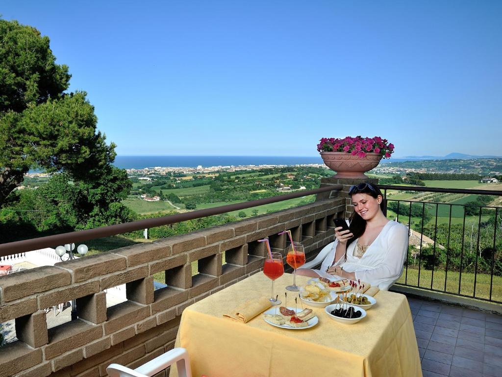 Eine Frau, die an einem Tisch mit Gläsern Wein sitzt. in der Unterkunft Hotel Bel Sit in Senigallia