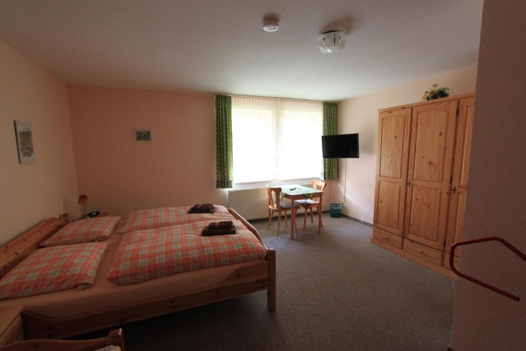 a bedroom with a bed and a desk and a window at Landhotel Gutsherrn-Klause in Dankerode