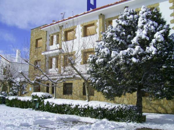 un edificio cubierto de nieve con un árbol delante de él en El Ciervo, en Villaciervos