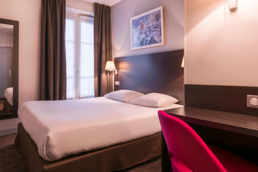 パリにあるオテル デ ゼクリヴァンのベッドとデスクが備わるホテルルームです。