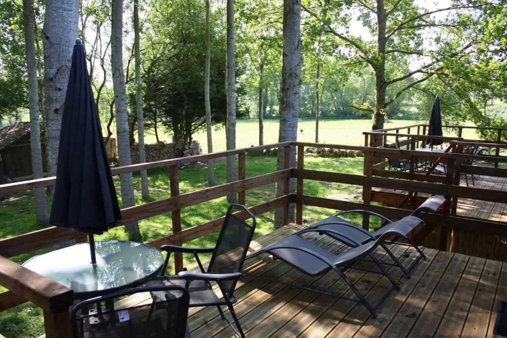 una terrazza con sedie, tavolo e ombrellone di Chambres d'hôtes la landrière a Mauléon