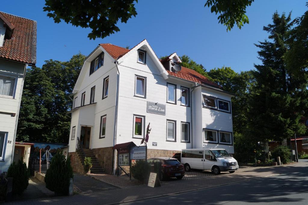 a white house with a car parked in front of it at Pension Mona Lisa in Braunlage