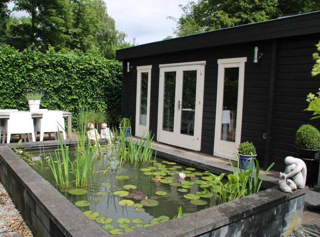 a garden with a pond in front of a black house at B&B Gaasterland in Harich