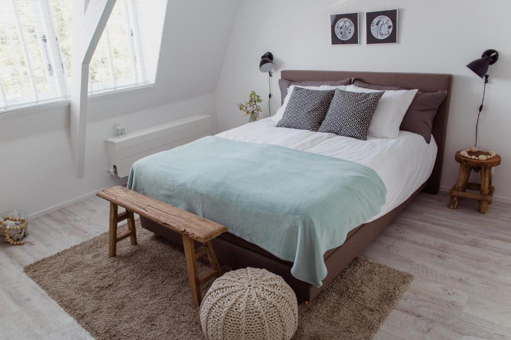 a bedroom with a large bed and a wooden bench at Studio De Bilt in De Bilt