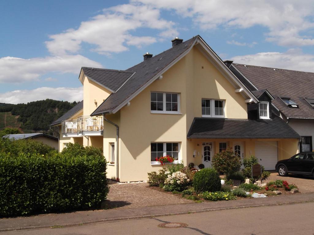 une maison jaune avec un toit noir dans l'établissement Ferienwohnungen Gibbert, à Pünderich