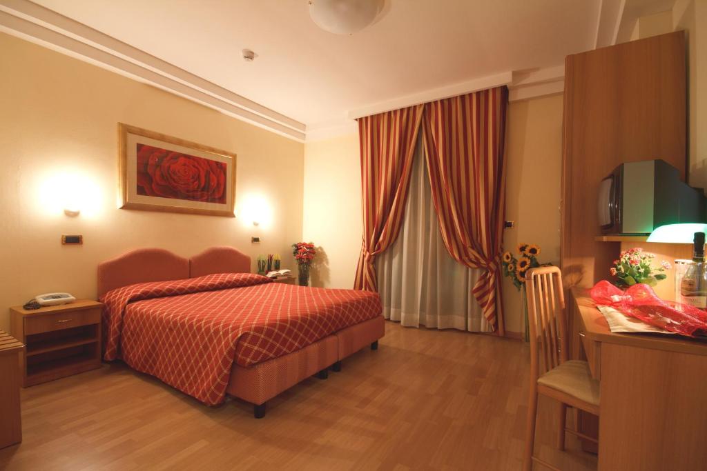 um quarto de hotel com uma cama com uma colcha vermelha em Hotel Villa Luca em Chianciano Terme