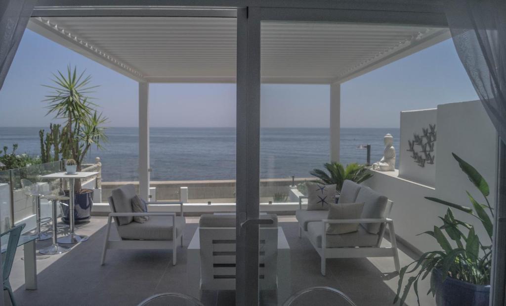 a patio with chairs and a view of the ocean at Beach-Front Bahia Dorada in Estepona