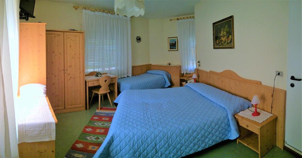 a bedroom with two blue beds and a desk at Hotel Zoldana in Forno di Zoldo