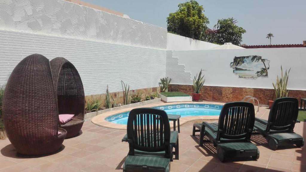 a group of chairs sitting next to a swimming pool at Casa Burgos in Corralejo